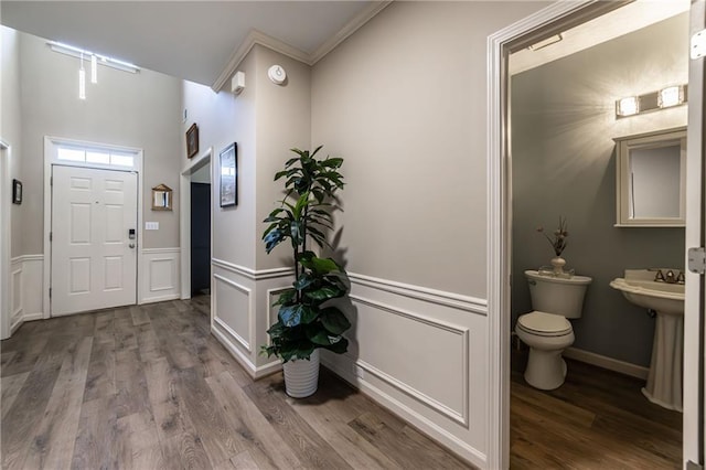 foyer with a wainscoted wall, a decorative wall, and wood finished floors