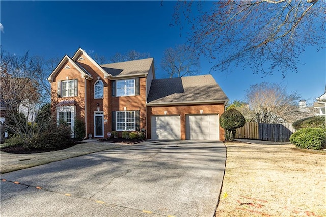 colonial inspired home with driveway, a garage, fence, and brick siding