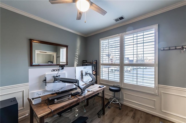 office with a wainscoted wall, wood finished floors, visible vents, and crown molding