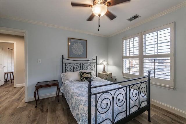 bedroom featuring baseboards, visible vents, crown molding, and wood finished floors