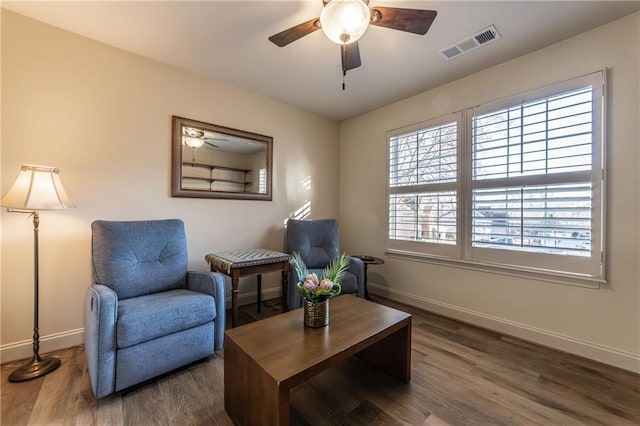 sitting room with a ceiling fan, visible vents, baseboards, and wood finished floors