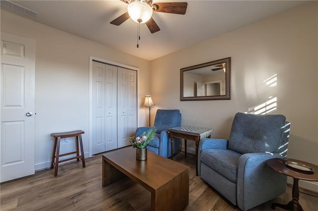 sitting room with a ceiling fan, visible vents, baseboards, and wood finished floors