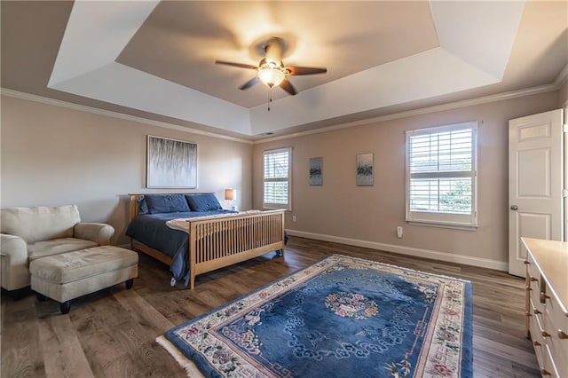 bedroom featuring a tray ceiling, multiple windows, wood finished floors, and baseboards