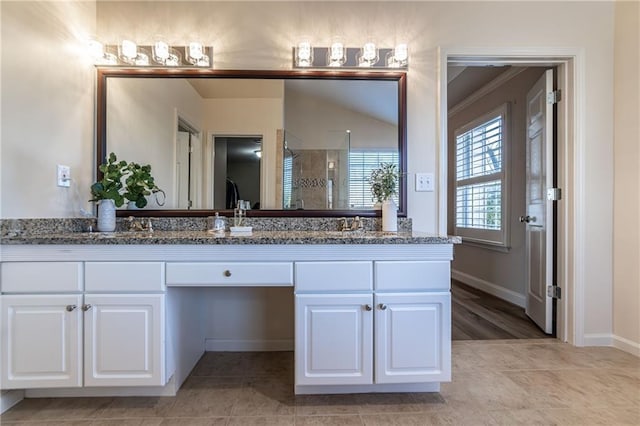 bathroom featuring double vanity, a stall shower, tile patterned floors, and baseboards