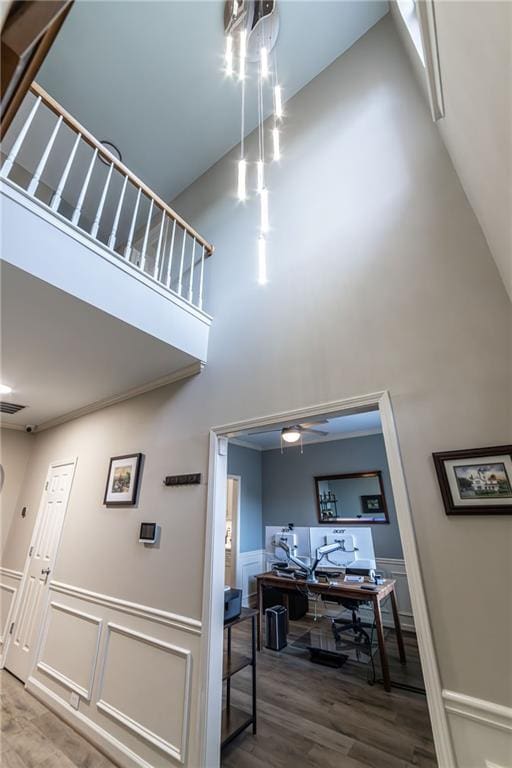 interior space with wainscoting, visible vents, a high ceiling, and wood finished floors