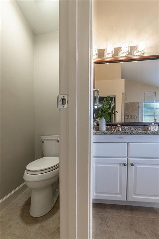 bathroom featuring baseboards, vanity, toilet, and tile patterned floors