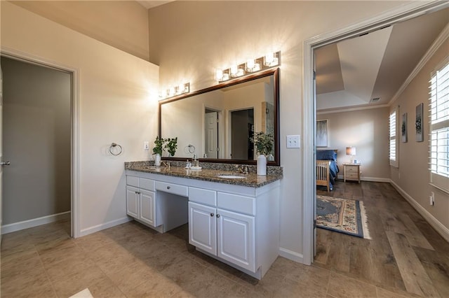 bathroom featuring baseboards, a tray ceiling, crown molding, and vanity