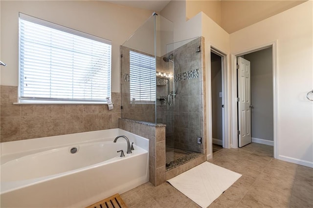 full bathroom featuring a stall shower, a garden tub, baseboards, and tile patterned floors