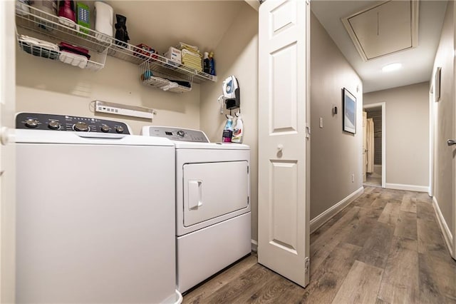 washroom with laundry area, attic access, baseboards, wood finished floors, and washing machine and dryer