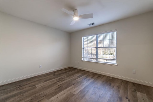 empty room featuring dark wood-style floors, ceiling fan, visible vents, and baseboards