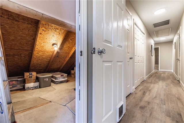 hall featuring baseboards, wood finished floors, visible vents, and attic access