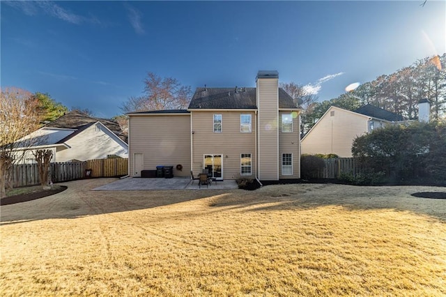 back of house featuring a chimney, a patio area, a fenced backyard, and a lawn