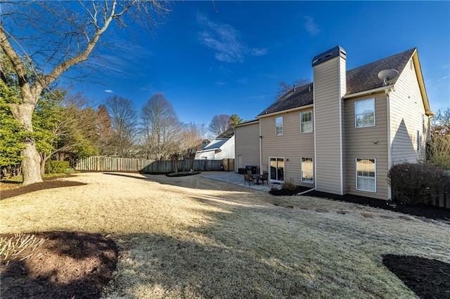 rear view of house with a patio, a chimney, and fence