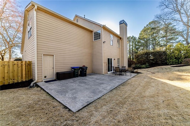 back of property featuring a chimney, a patio area, and fence