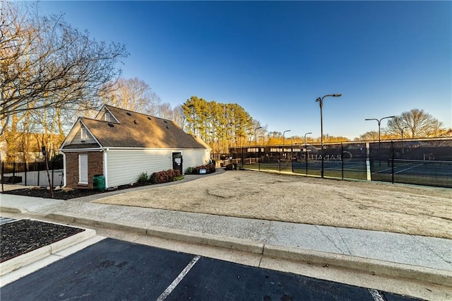 exterior space with a tennis court and fence