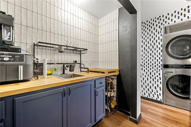 1357 Railroad Ave, Sugar Hill, GA 30518 - kitchen featuring stacked washer / drying machine, butcher block countertops, blue cabinetry, light wood-style floors, and a textured ceiling