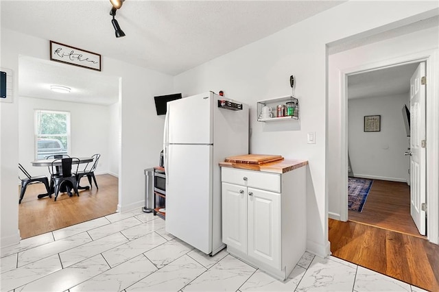 1357 Railroad Ave, Sugar Hill, GA 30518 - kitchen featuring freestanding refrigerator, light marble finish floors, butcher block countertops, white cabinets, and baseboards