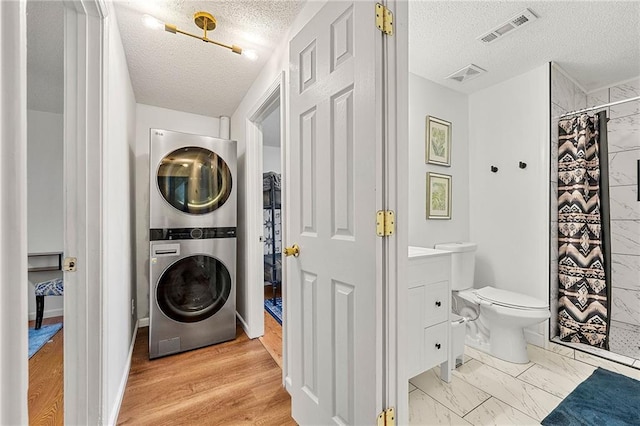 1357 Railroad Ave, Sugar Hill, GA 30518 - washroom with stacked washer and clothes dryer, a textured ceiling, and baseboards