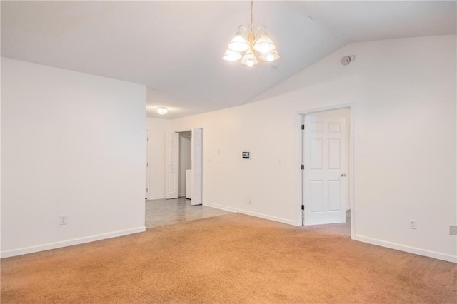 empty room with vaulted ceiling, an inviting chandelier, and carpet