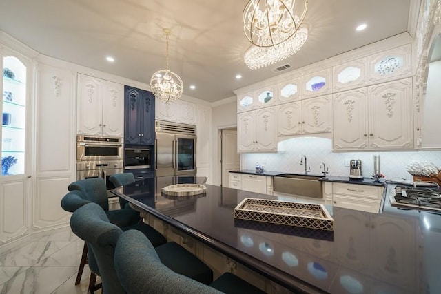 kitchen with appliances with stainless steel finishes, hanging light fixtures, tasteful backsplash, a notable chandelier, and white cabinets