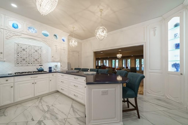 kitchen with a chandelier, tasteful backsplash, white cabinetry, light tile floors, and pendant lighting