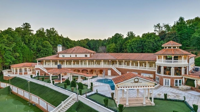 back of property with a balcony, a patio area, a gazebo, a lawn, and a fenced in pool