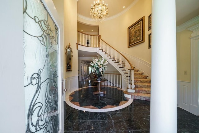 foyer entrance with ornamental molding, an inviting chandelier, dark tile floors, and a high ceiling