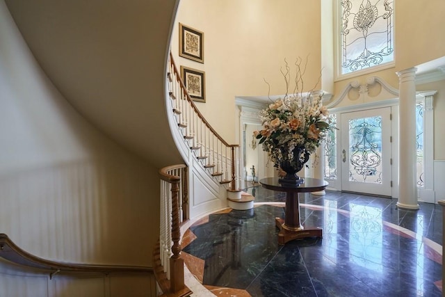 tiled foyer entrance with decorative columns, a high ceiling, and a healthy amount of sunlight