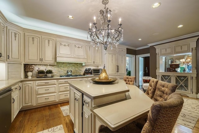 kitchen with appliances with stainless steel finishes, a kitchen island, a breakfast bar area, a chandelier, and light hardwood / wood-style flooring