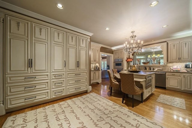 kitchen with decorative light fixtures, an inviting chandelier, appliances with stainless steel finishes, light hardwood / wood-style flooring, and cream cabinets