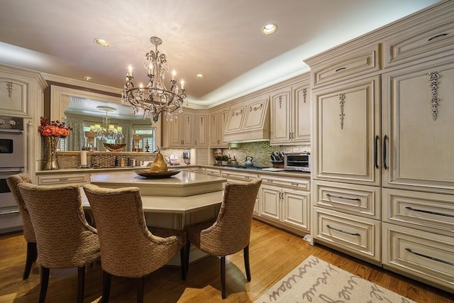 kitchen with light hardwood / wood-style flooring, pendant lighting, a notable chandelier, and a kitchen bar