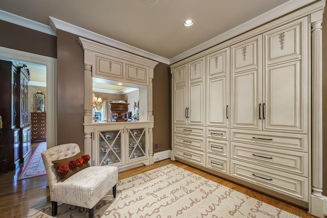 living area with an inviting chandelier, crown molding, and light wood-type flooring