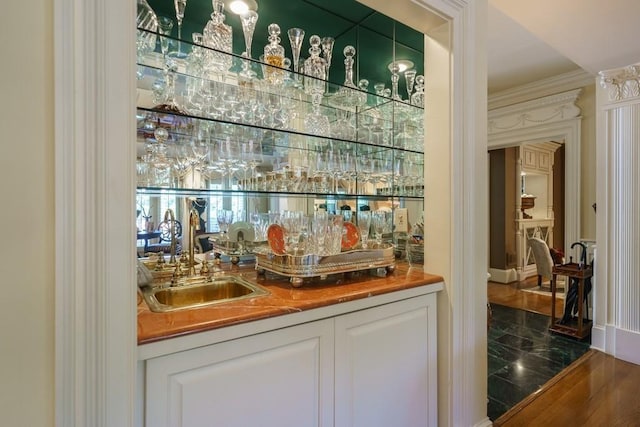 bar featuring sink, white cabinets, and dark tile flooring