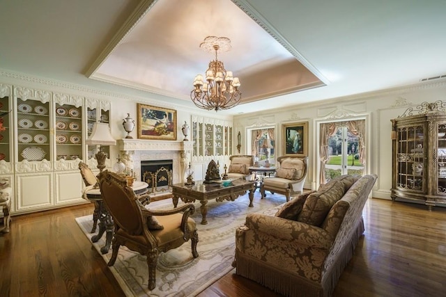 living area featuring a notable chandelier, crown molding, dark hardwood / wood-style floors, and a raised ceiling