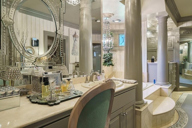 interior space featuring decorative columns, a bathtub, a chandelier, ornamental molding, and vanity