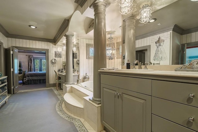 bathroom with an inviting chandelier, ornate columns, crown molding, vanity, and tiled tub