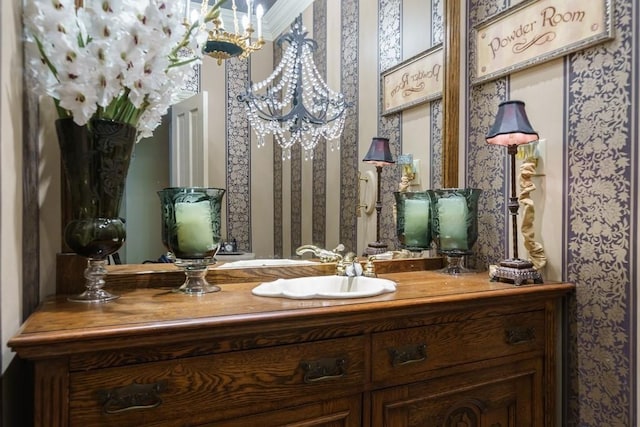 bathroom featuring an inviting chandelier, ornamental molding, and vanity