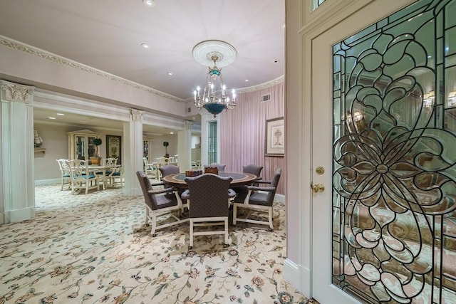 carpeted dining area with an inviting chandelier, ornamental molding, and ornate columns