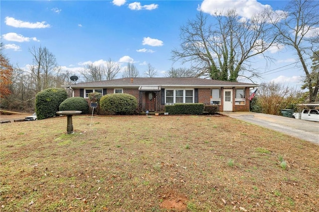 ranch-style home featuring driveway, brick siding, and a front yard