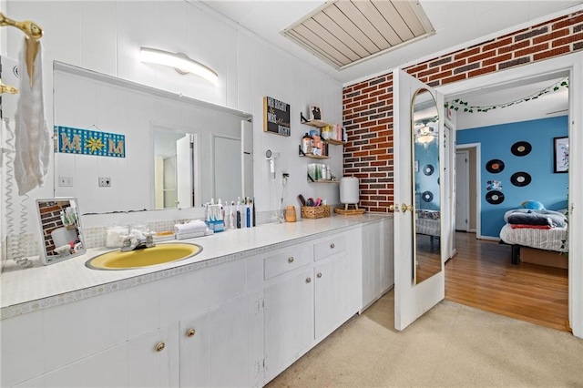 bathroom featuring brick wall and vanity