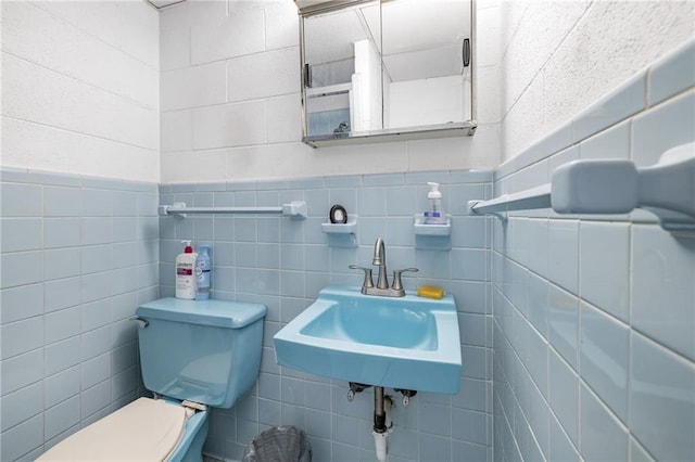 half bathroom with a sink, tile walls, and toilet