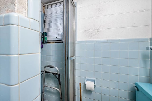 full bathroom with toilet, a stall shower, and tile walls