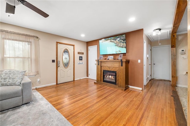 living area with light wood finished floors, attic access, baseboards, and a glass covered fireplace