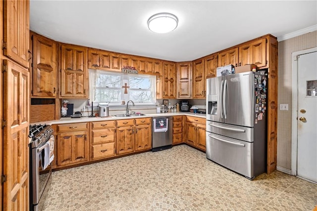 kitchen with brown cabinets, stainless steel appliances, a sink, and light countertops