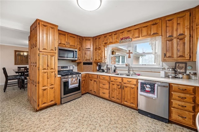 kitchen with brown cabinetry, stainless steel appliances, a sink, and light countertops