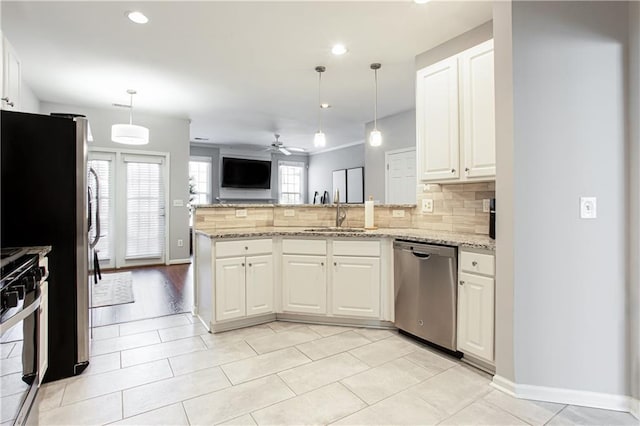 kitchen with decorative backsplash, appliances with stainless steel finishes, open floor plan, a peninsula, and a sink