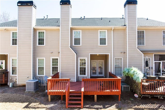 back of property with cooling unit, french doors, roof with shingles, and a chimney