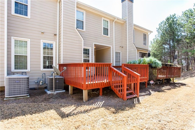 rear view of house with central AC unit, a chimney, and a wooden deck