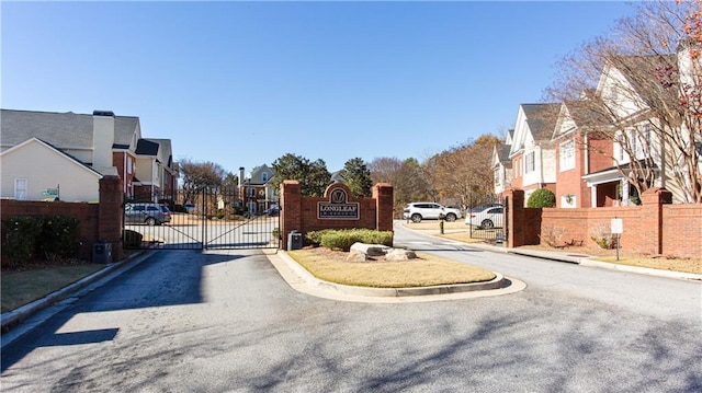 view of street featuring curbs, a gated entry, a residential view, and a gate