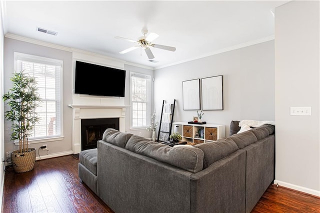 living room featuring dark wood-style floors, plenty of natural light, a fireplace, and visible vents